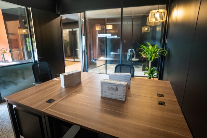 Bureau privatif de La Gravade : table en bois et boîtes de bienvenue, mur noir