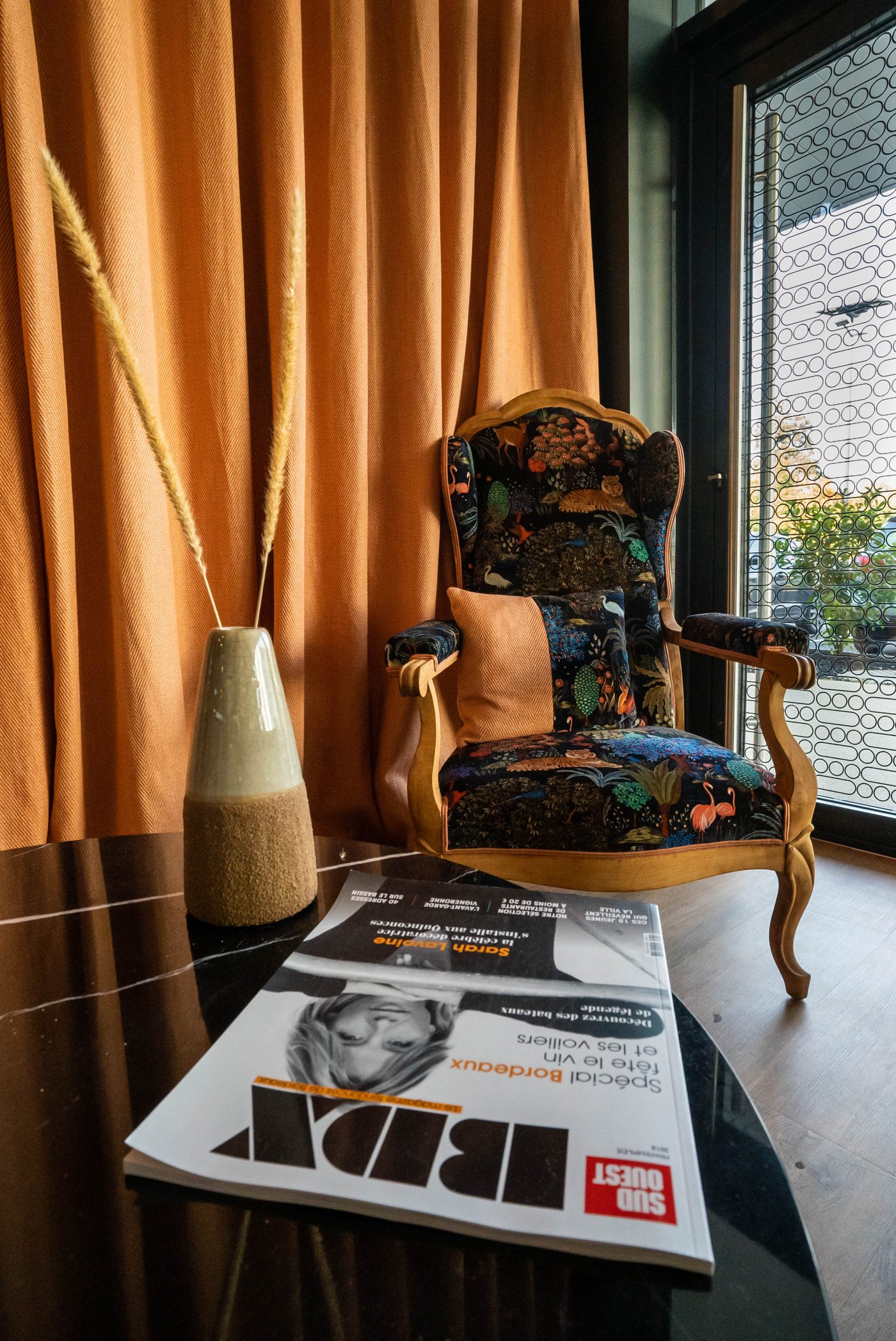 Salon de La Gravade : fauteuil vintage à motif, rideaux terracotta