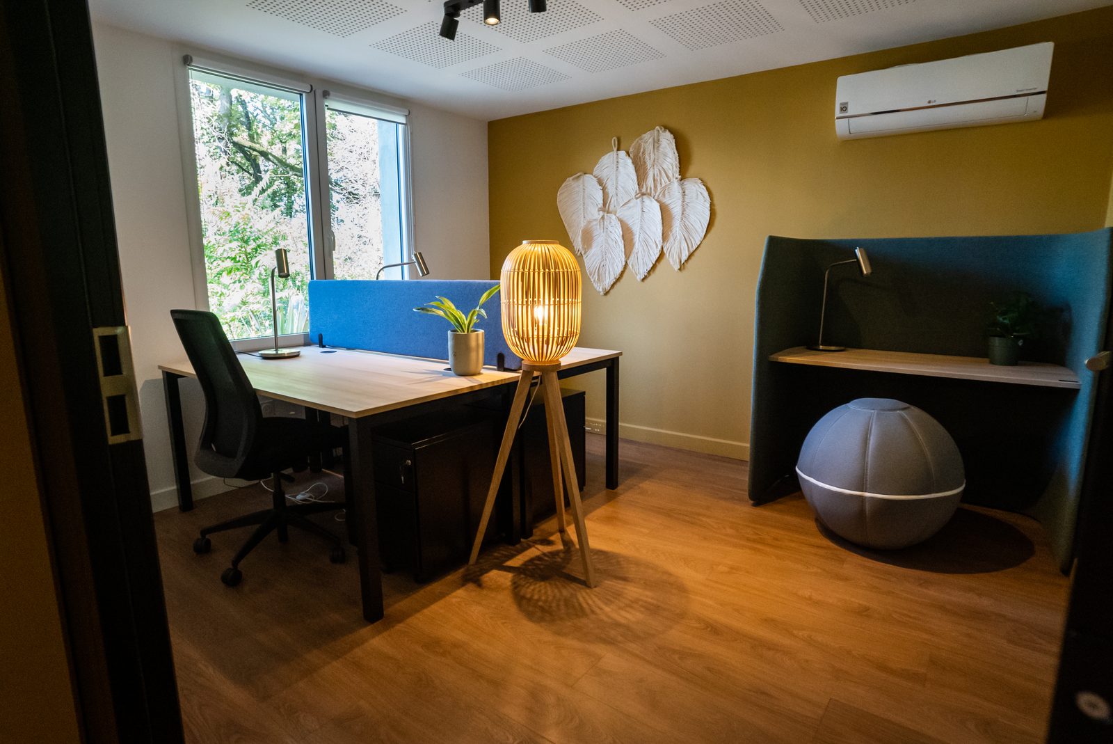 Bureau Objectif au Vigean : plan de travail face à la fenêtre, lampe en osier, fauteuil bulle et mur moutarde