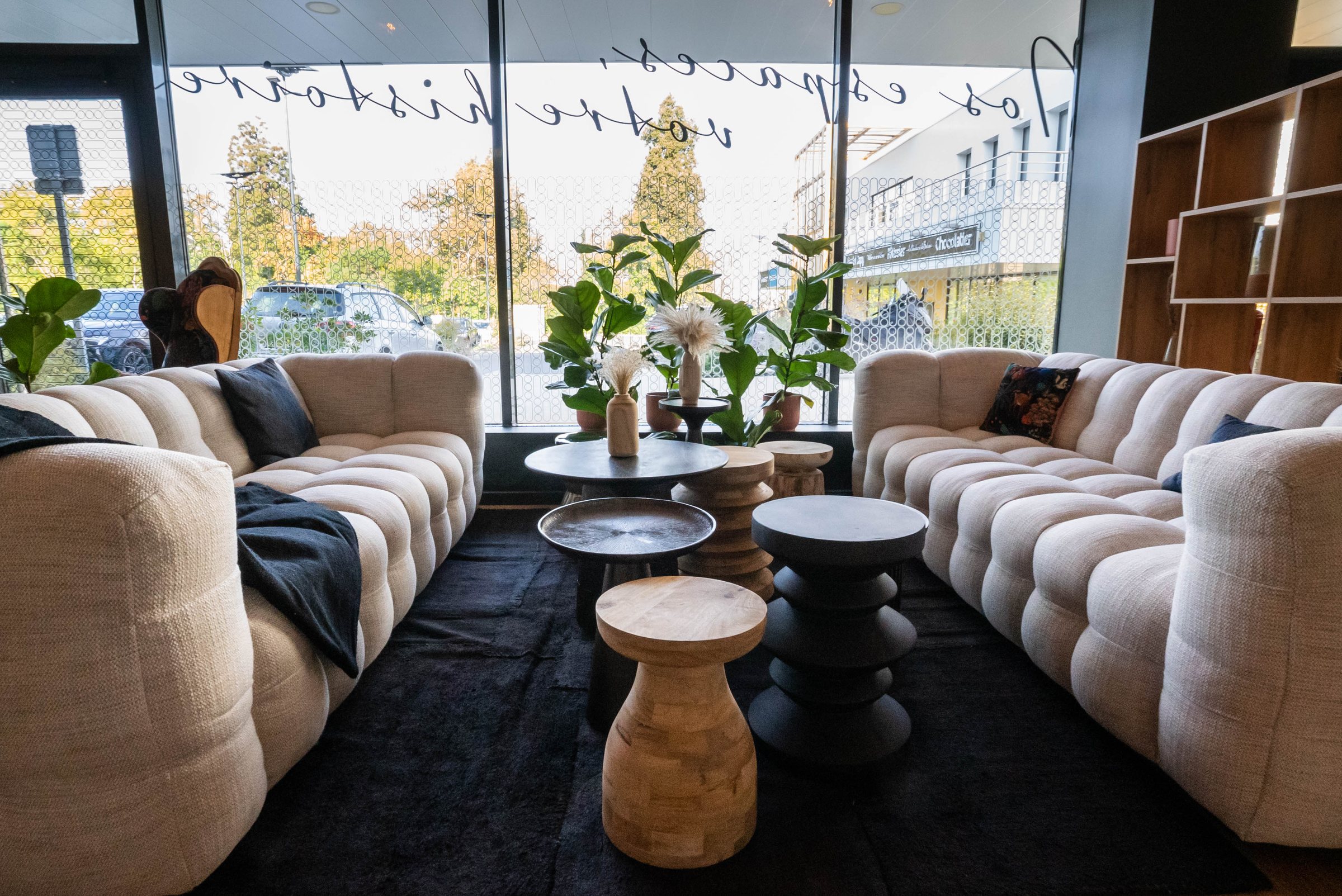 Salon lounge de La Gravade : grands canapés clairs, tables basses en bois, vitrine gravée « Nos espaces, votre histoire »